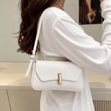 Bolsa Amélia branca usada no ombro, com aba curva e detalhe dourado