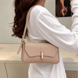 Bolsa Amélia nude usada no ombro, com aba curva e detalhe dourado